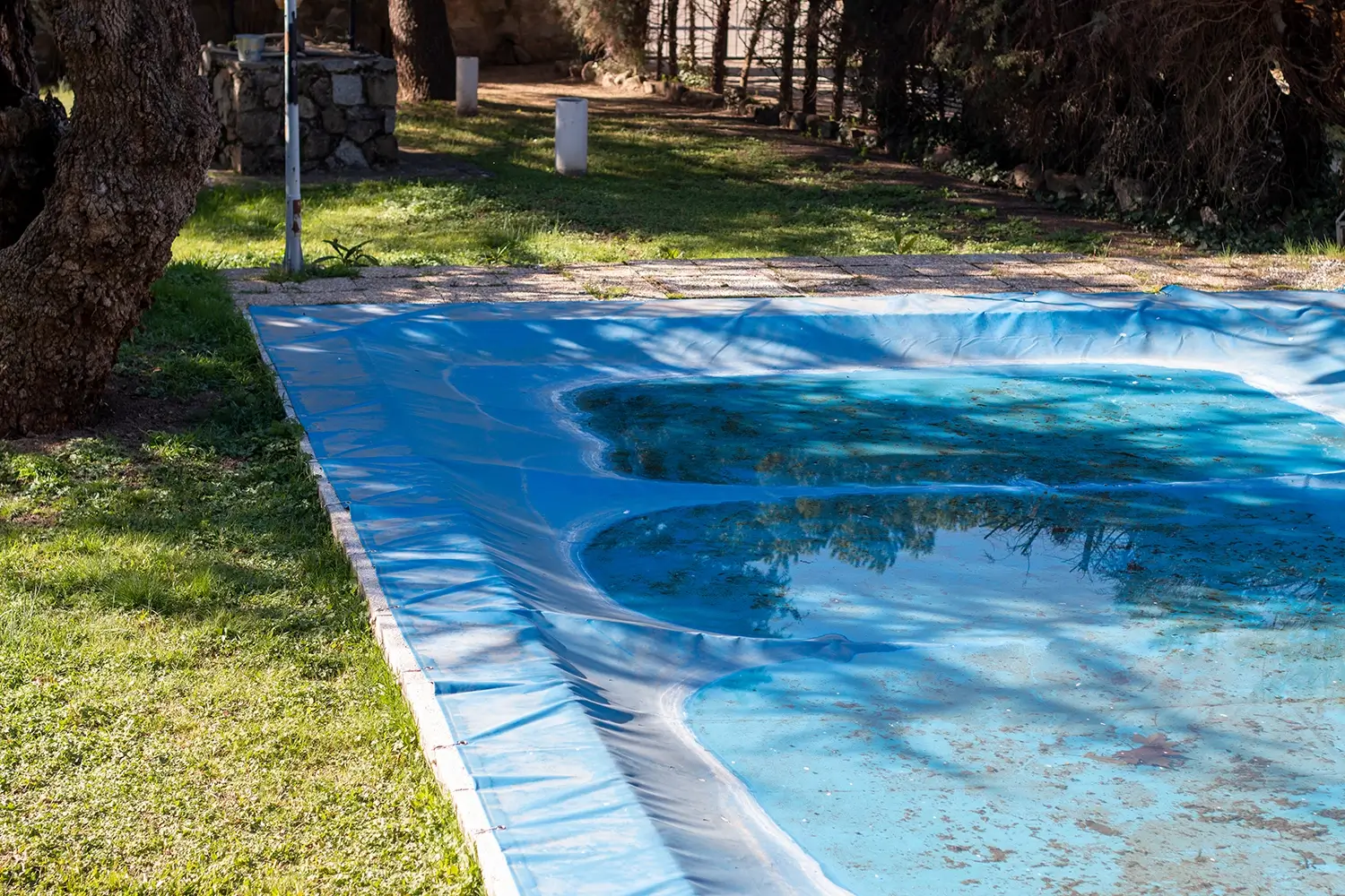 Blue tarp is covering in-ground pool, protecting it from the elements during off-seasons