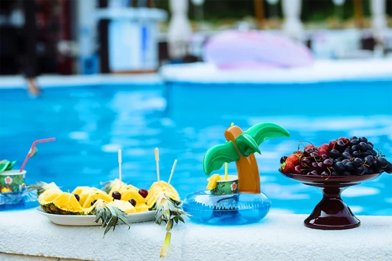 Fruit skewers and platters poolside with themed palm tree drink holder