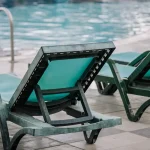 Close up of the back side of a green pool chair facing the pool