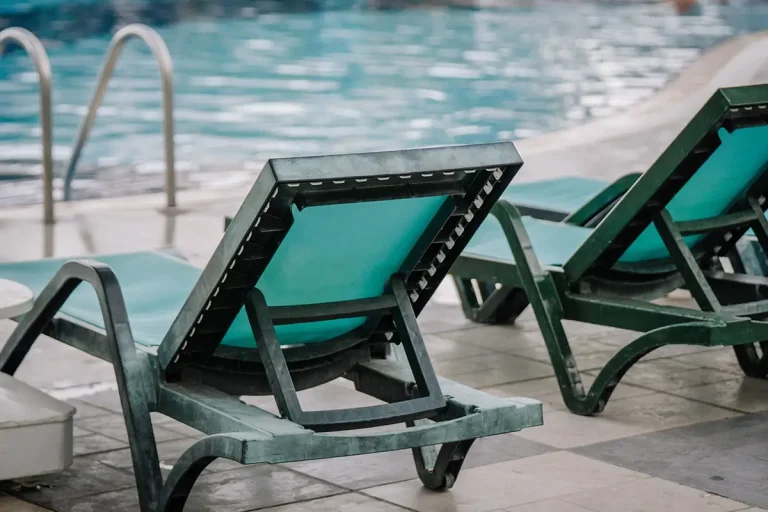Close up of the back side of a green pool chair facing the pool