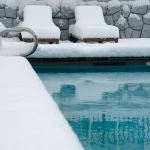 Pool with deck and chairs covered in snow