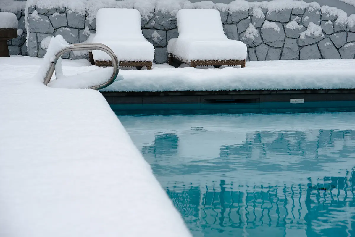 Pool with deck and chairs covered in snow