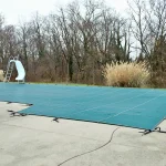 backyard swimming pool with pool slide tarped up and closed down for winter