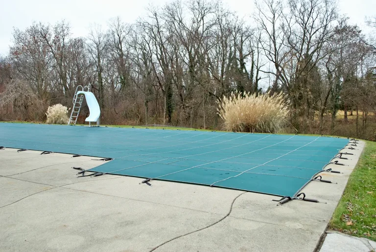 backyard swimming pool with pool slide tarped up and closed down for winter