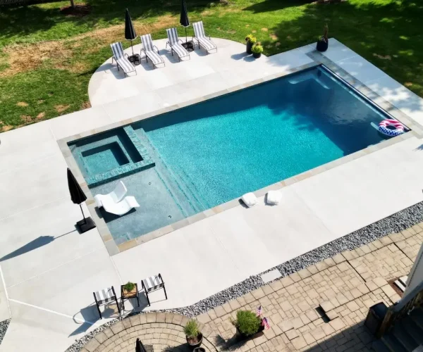 View of clean backyard pool with tanning chairs, hot tub, and patio seating
