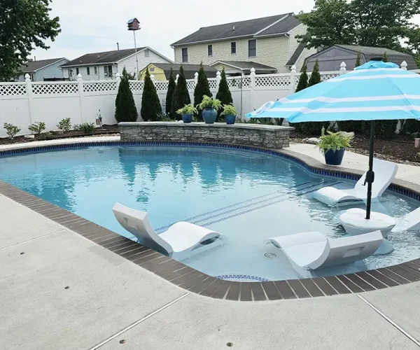 Backyard pool that has a tanning ledge with four loungers in the pool.